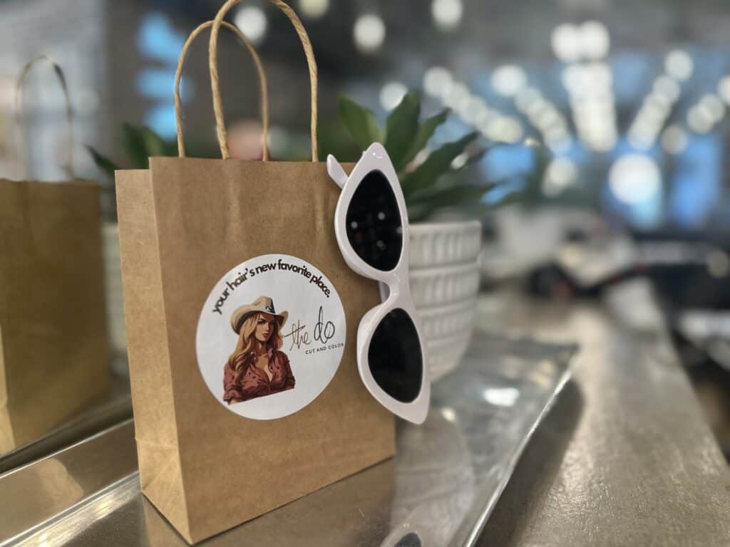 Gift bag from The Do Cut and Color Beauty Salon with a pair of sunglasses clipped on.